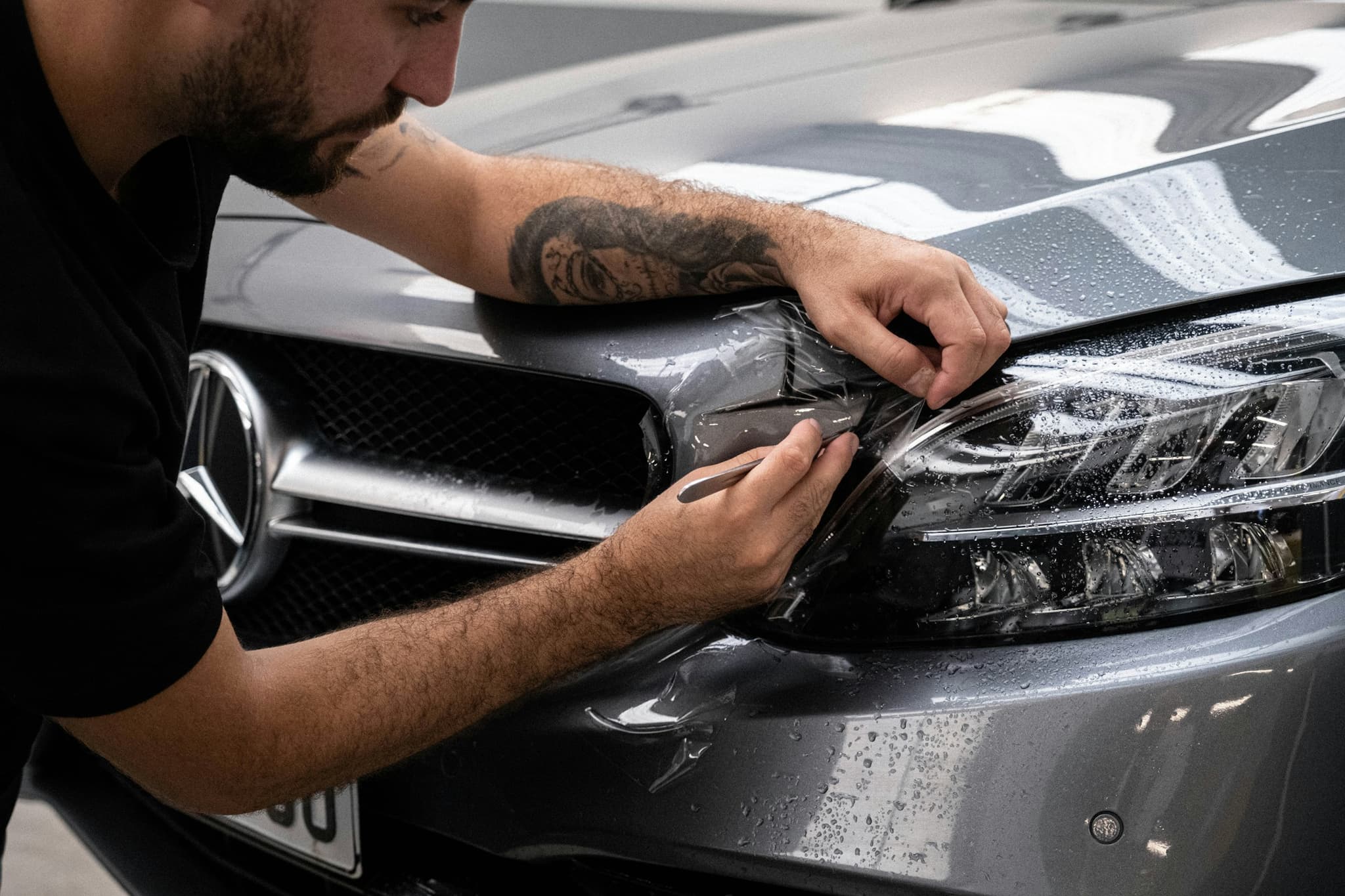 A detailer working by hand on the front of a vehicle